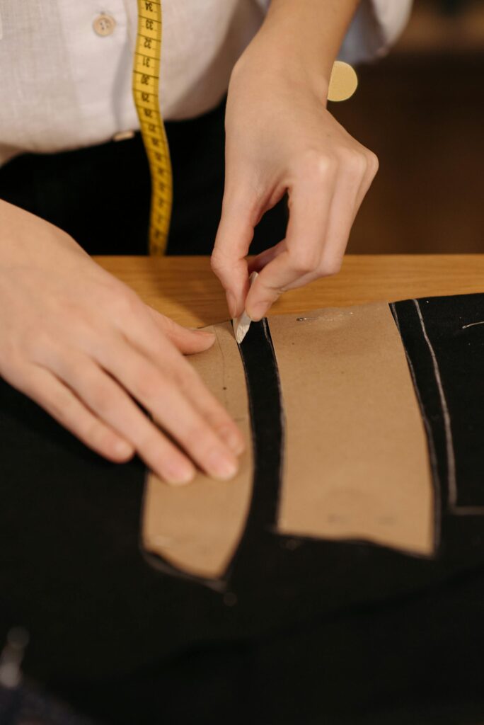 Tailor tracing a pattern on black fabric during a bespoke fitting appointment